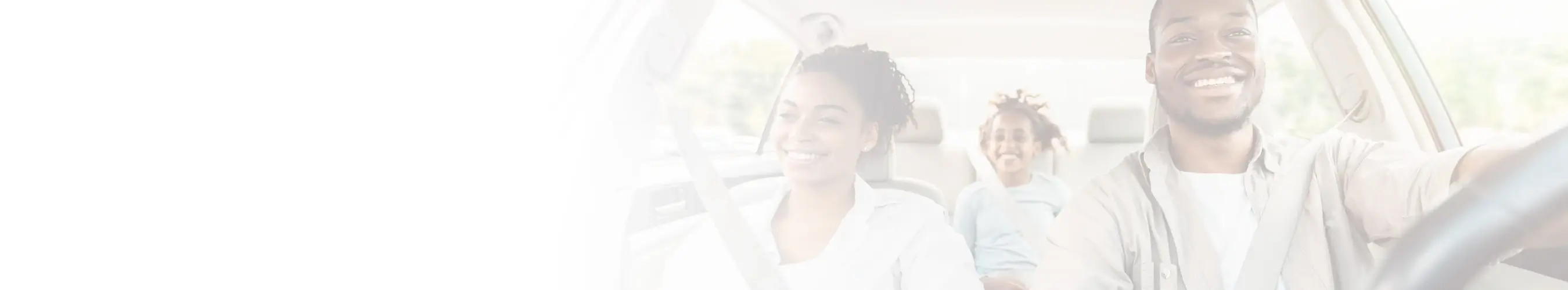 Smiling family driving in a car together, with child seated in the backseat